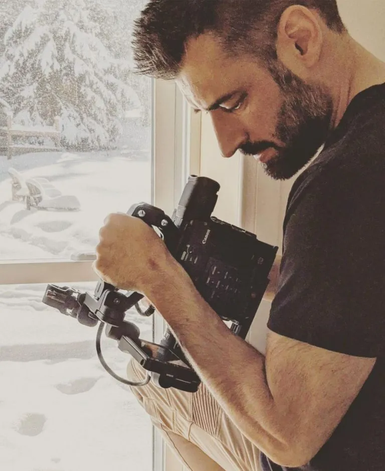 Alexandre Comtois, caméra Canon en main, en plein tournage près d'une fenêtre, en hiver
