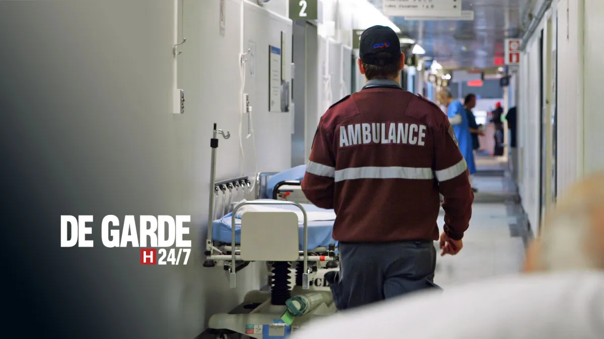Image officielle de l'émission De garde 24/7 : un ambulancier marche de dos dans un corridor d'hôpital
